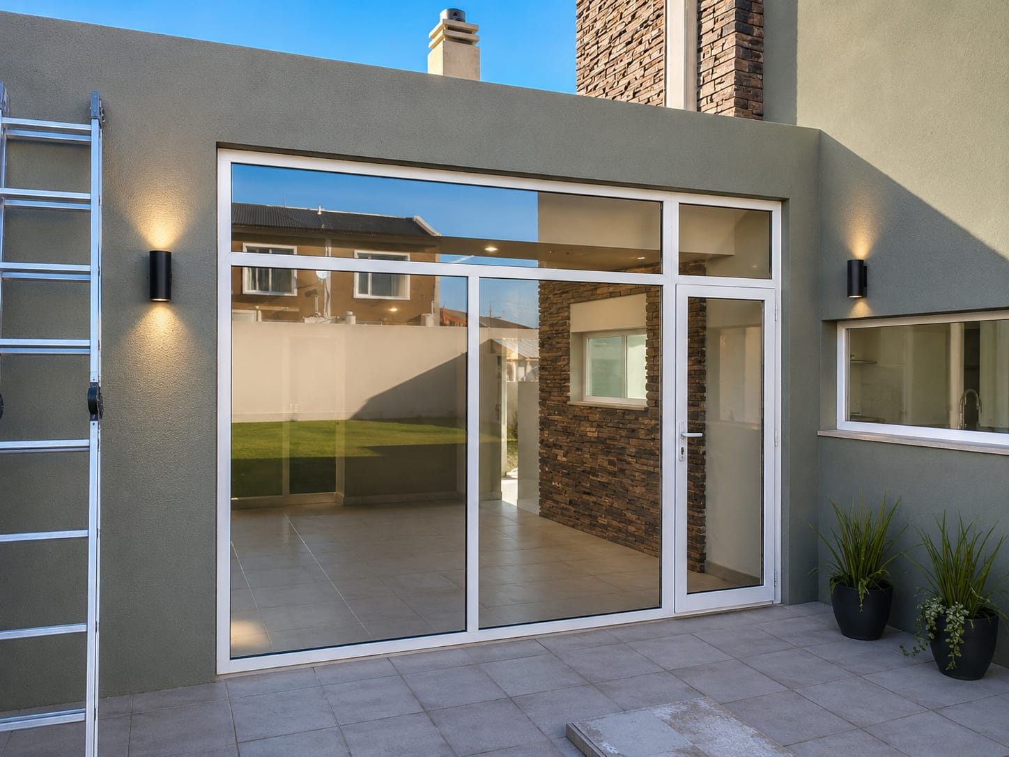 Cerramiento de aluminio blanco con amplios paños vidriados y puerta de acceso